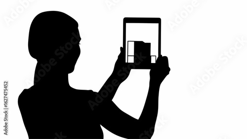 Silhouette of a person holding a tablet displaying a building design in augmented reality application