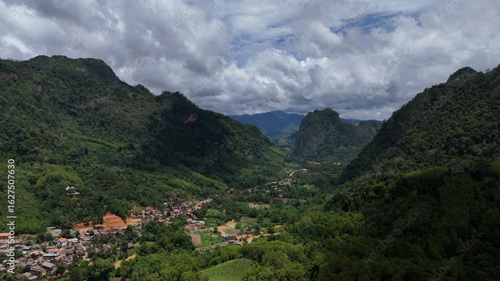 Naklejka premium Cloudy mountain landscape with green forests and peaks