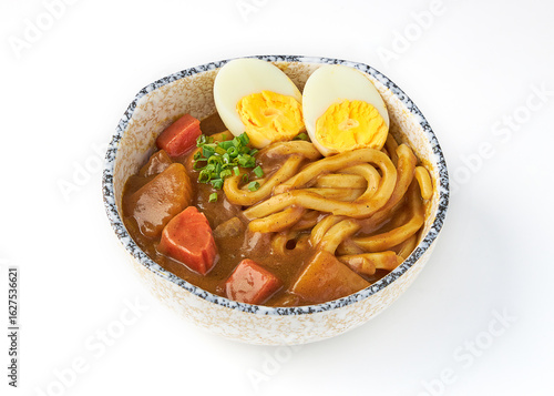 Bowl of Japanese curry udon with thick noodles, hearty curry sauce, tender carrots, potatoes, and boiled egg, garnished with fresh green onions, served in ceramic bowl