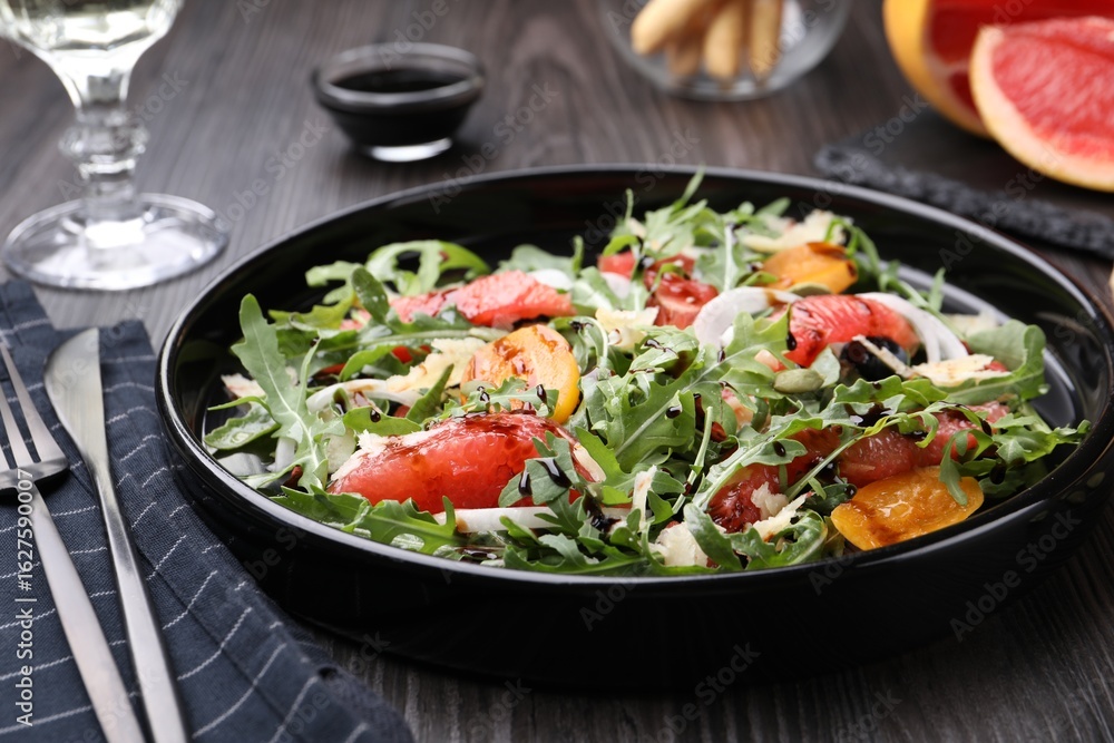 Tasty salad with arugula, cheese, grapefruit, vegetable and balsamic sauce on dark wooden table, closeup Tasty salad with arugula, cheese, grapefruit, vegetable and balsamic sauce on dark wooden table, closeup