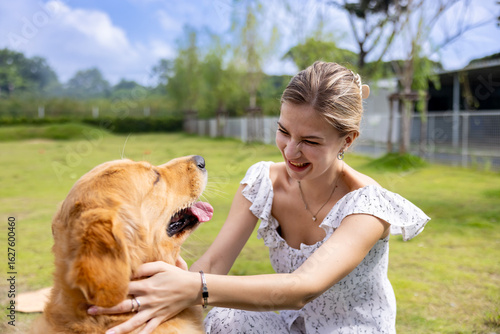 Caucasian woman hugging her cute energetic golden retriever dog in the outdoor park during summer for animal lover and pet sitter training concept