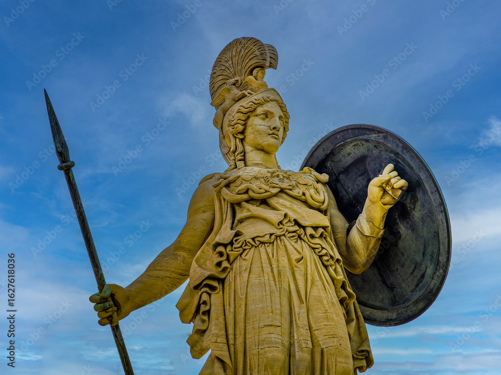 Obraz premium Athena, the Greek goddess of wisdom and knowledge, with a helmet, a sharp spear and a large shield. Craftsmanship highlights the power of the revered deity, set against a blue sky backdrop.