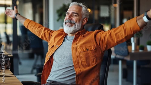 Relaxed mature man in an office setting, arms outstretched