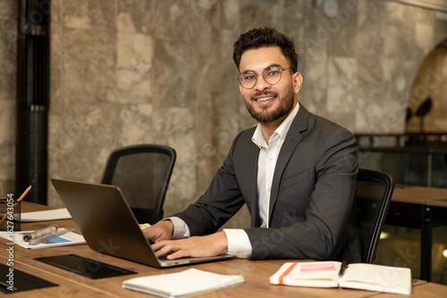 Dark-haired young manager working in the office and looking confident