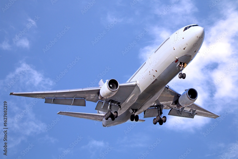 Fototapeta premium Passenger airplane taking off under cloudy blue sky
