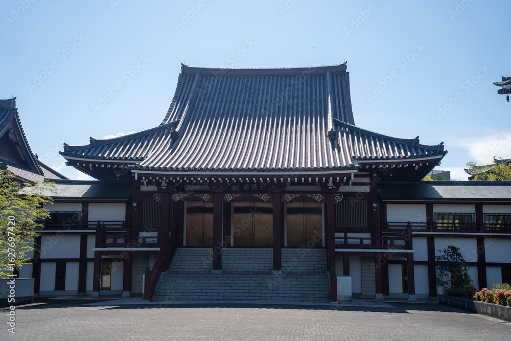 Fototapeta premium Traditional temple nestled within a bustling cityscape, blending cultural heritage with urban life.