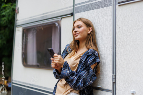 Woman driver enjoy camper parking rv area using phone app to plan next destination of travel.