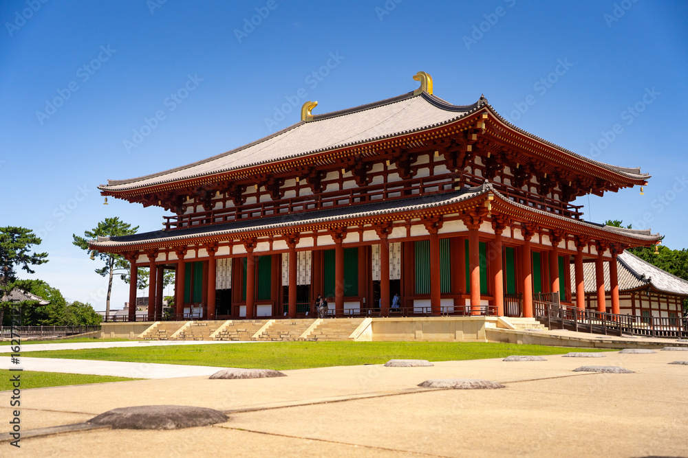 Fototapeta premium Majestic big red temple set amidst expansive, serene temple grounds with lush greenery.