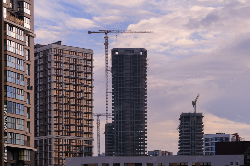 Fototapeta premium Construction of buildings and high-rise cranes against the sky