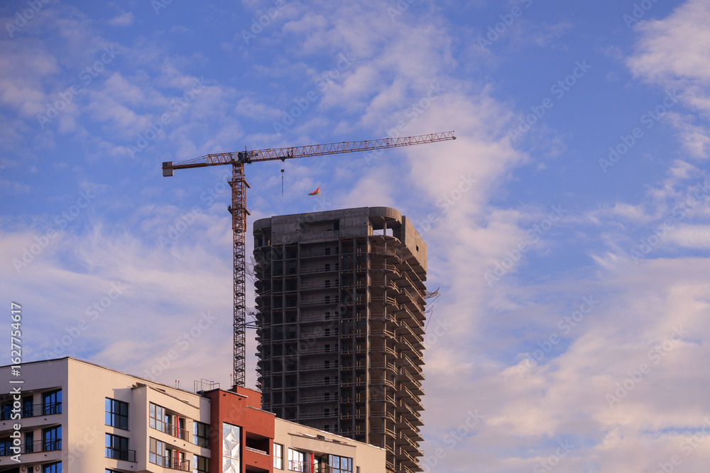 Fototapeta premium Construction of buildings and high-rise cranes against the sky