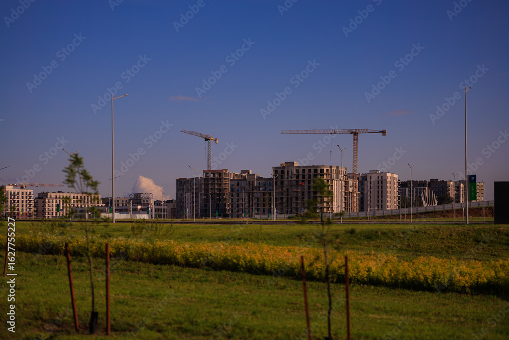 Fototapeta premium Construction of buildings and high-rise cranes against the sky