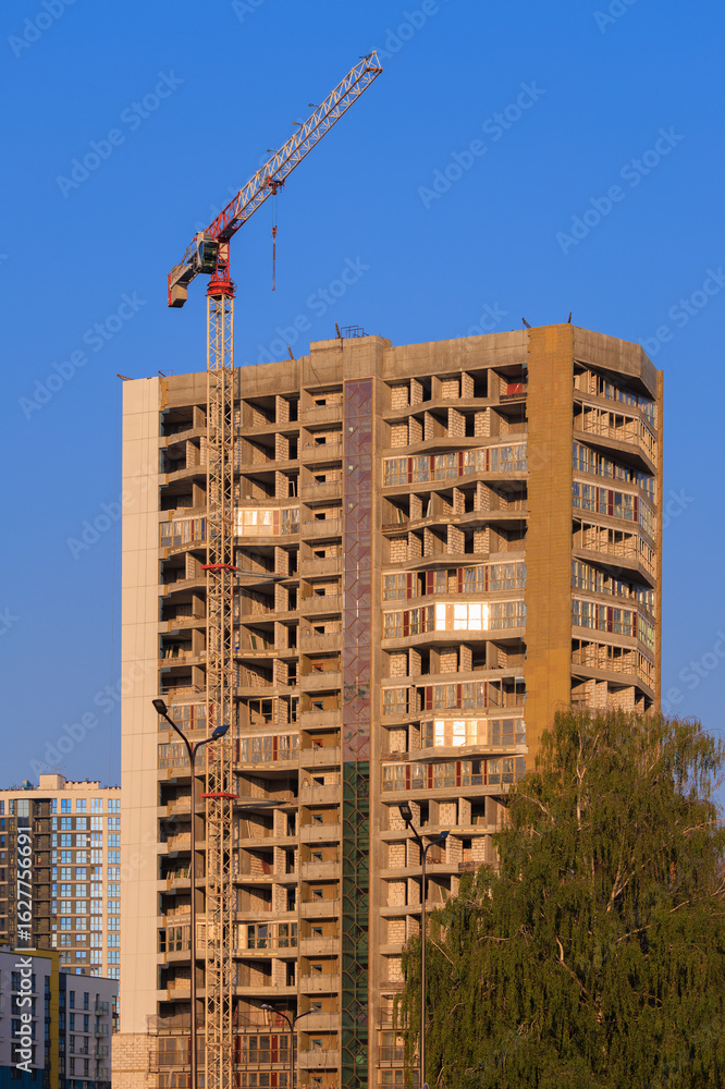 Fototapeta premium Construction of buildings and high-rise cranes against the evening sky