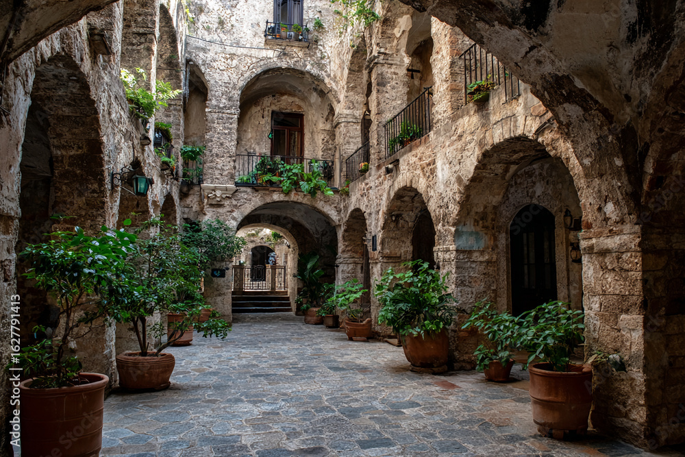 Fototapeta premium Stone courtyard with arched walkways, potted plants
