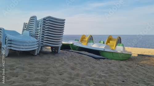 Stack of sun loungers on the beach.  Start or end of the summer season at the resort city. Heap of sunbeds at the coastline.