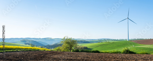 countryside landscape in luxemburg with wind turbine under blue sky in spring