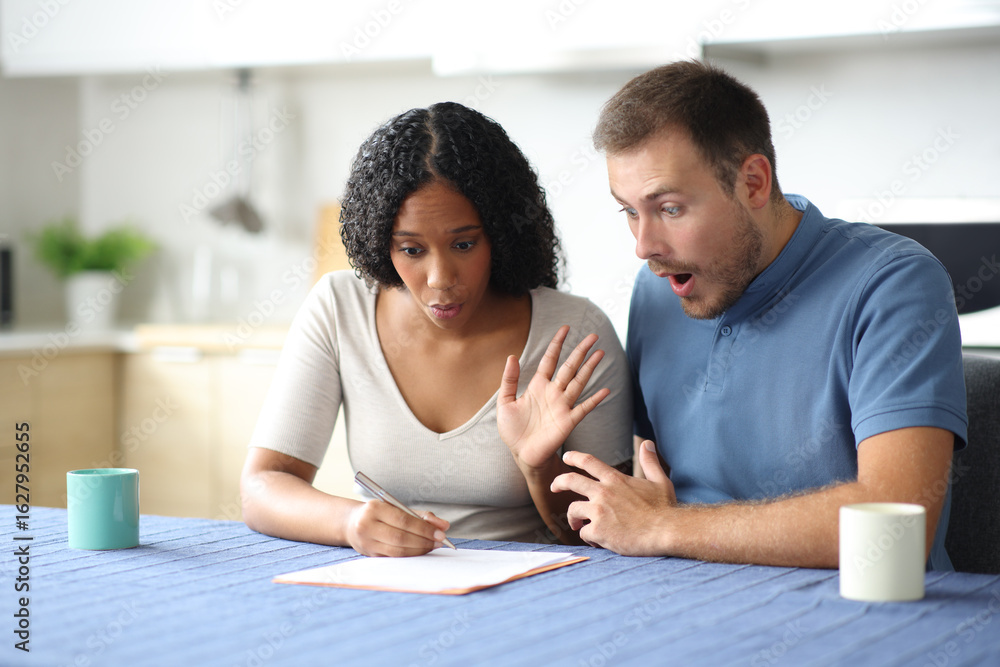Obraz premium Amazed interracial roommates reading contract in a kitchen