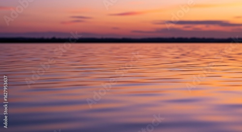 Wallpaper Mural Calm lake water reflecting a vibrant sunset sky with orange, pink, and purple hues, and a distant treeline on the horizon. Torontodigital.ca