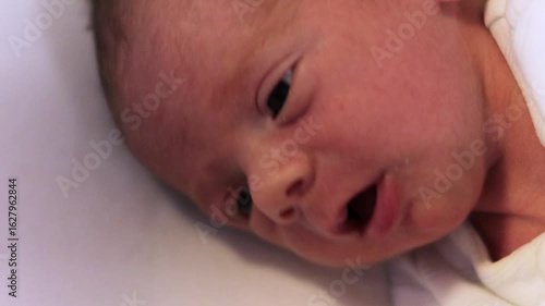 Adorable newborn baby making faces on white background
