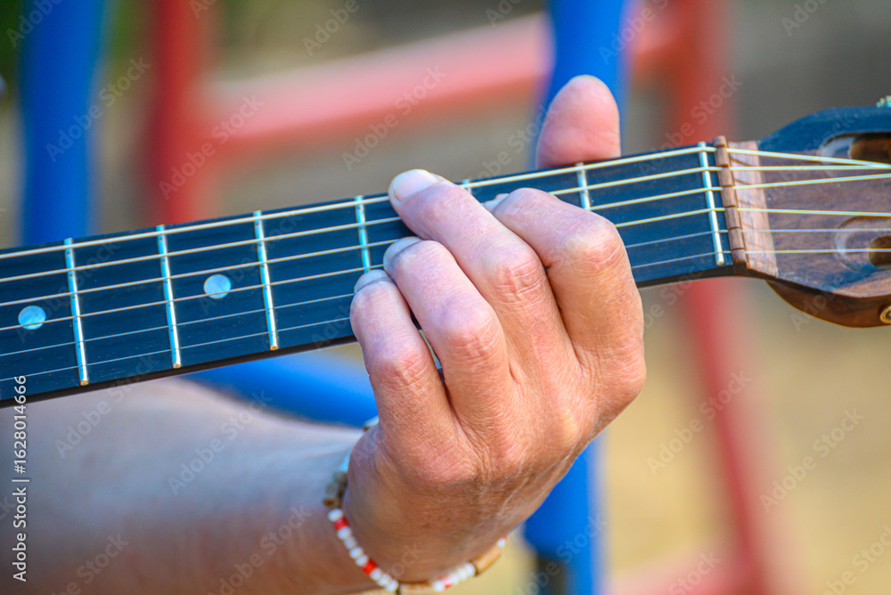 Fototapeta premium Fingers pressing down on the strings of an acoustic guitar. Playing instrument.