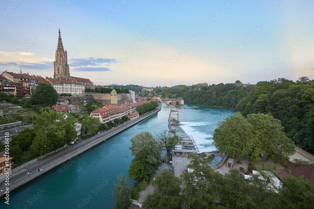 Naklejka premium View of the Aare River with buildings and a historic tower in Bern during twilight hours