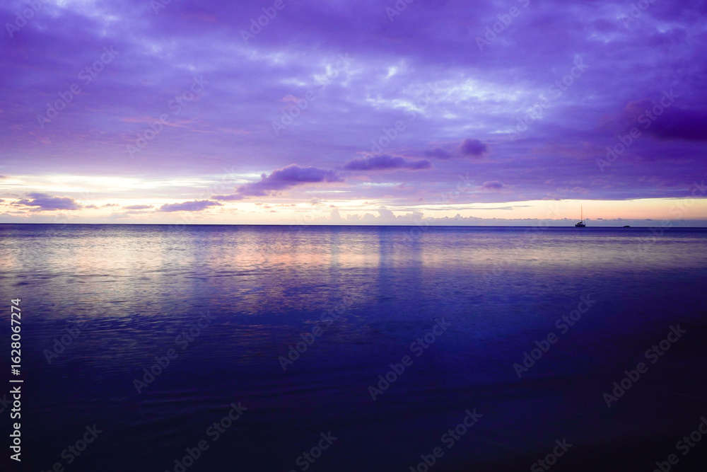 Obraz premium A wide ocean, pastel-colored skies with soft clouds, and calm waters create a dreamy sunrise atmosphere. Sun and clouds at dawn on the Baltic Sea beach of 18586 Göhren, Rügen Island