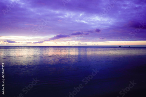 Fototapeta Naklejka Na Ścianę i Meble -  A wide ocean, pastel-colored skies with soft clouds, and calm waters create a dreamy sunrise atmosphere. Sun and clouds at dawn on the Baltic Sea beach of 18586 Göhren, Rügen Island
