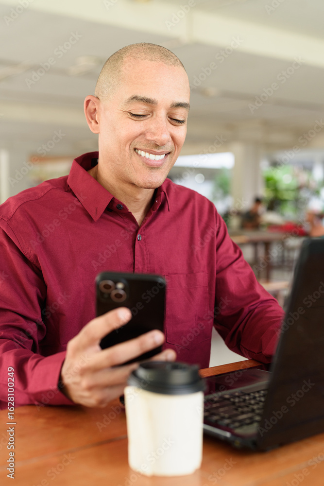 Bald man working on laptop computer at outdoor coffee shop in business or campus setting Bald man working on laptop computer at outdoor coffee shop in business or campus setting