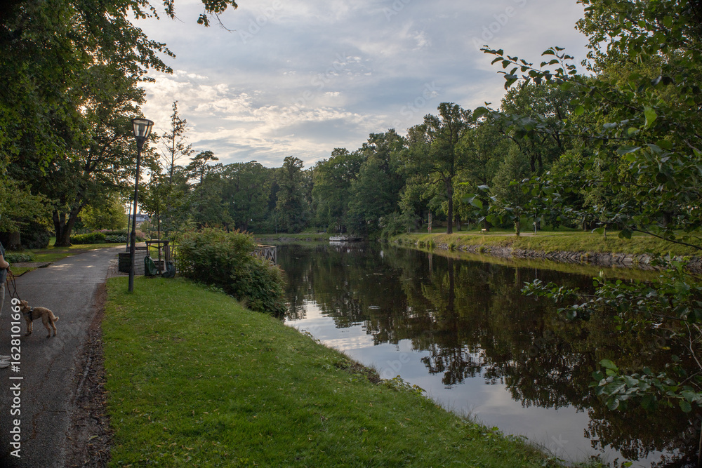Obraz premium Scenic view of Orebro parks next to the flowing creek surrounded by natural greenery in central Sweden Orebro County