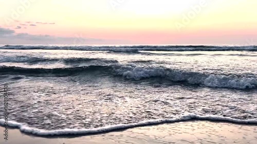 Peaceful sea waves under a pastel pink sunrise sky with the sun touching the horizon. Ideal for meditation videos, travel content, nature backgrounds, or romantic visual themes