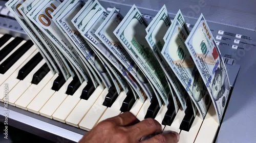 A stack of dollar bills on top of a music keyboard.