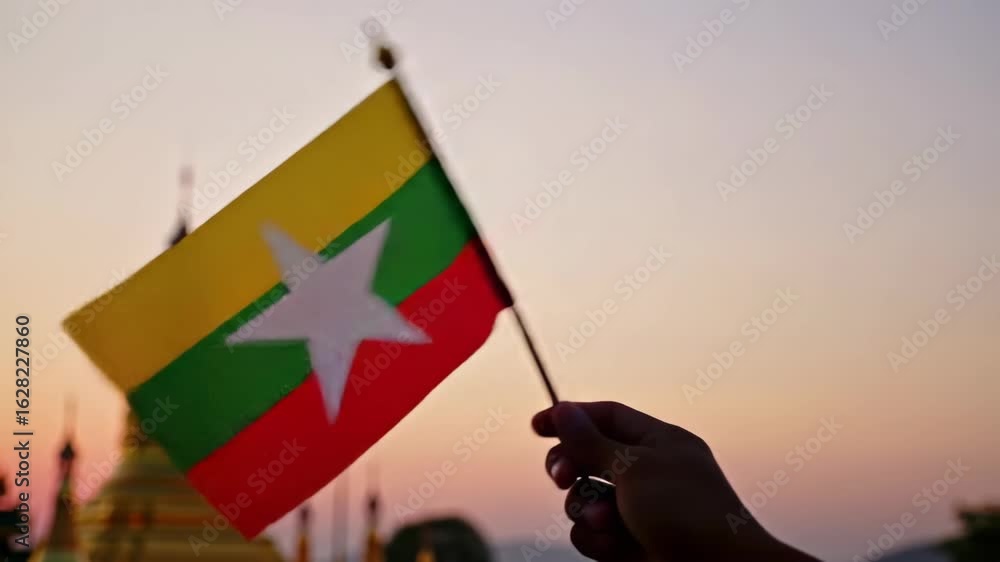Beautiful sunset with Myanmar flag waving over a golden pagoda in Southeast Asia