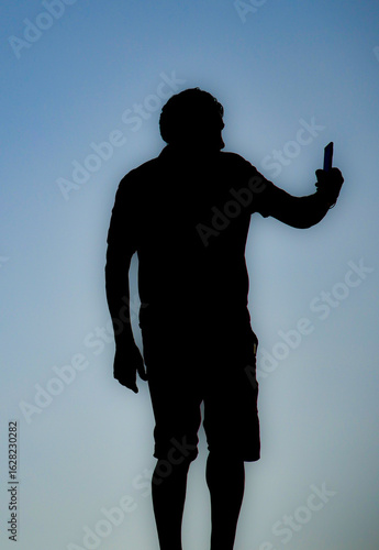 Mann mit Smartphone im Sonnenuntergang