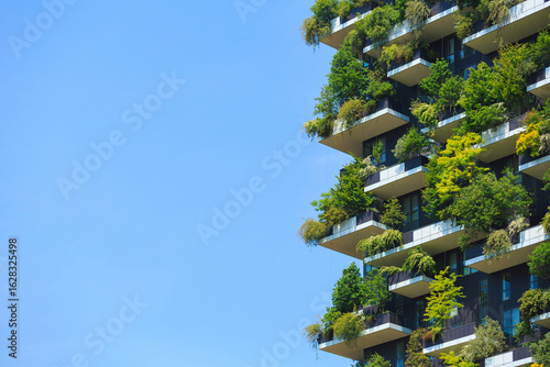 Foto Vibrant vertical garden on energy efficient building, featuring lush greenery on balconies throughout the facade against a clear blue sky