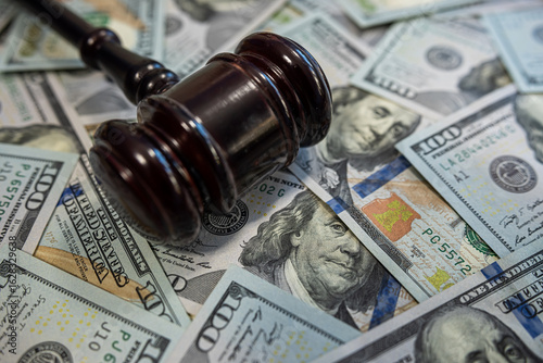 Gavel on hundred dollar bills – Law and money, justice system, legal fees or corruption concept