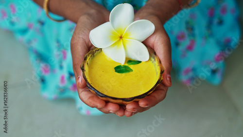A female hands holding homemade facial in bowl. Ayurvedic face pack of Haldi (Turmeric), Rose water and leaves. mortar of Ubtan for skincare. Natural way for skin beauty using since ancient India