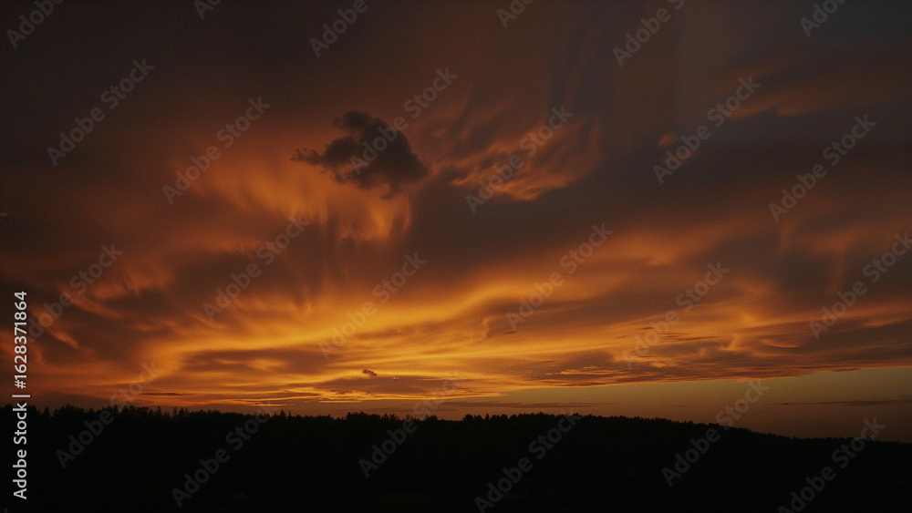 Obraz premium Dramatic Orange and Red Sunset Sky with Wispy Clouds Over Dark Horizon image photo