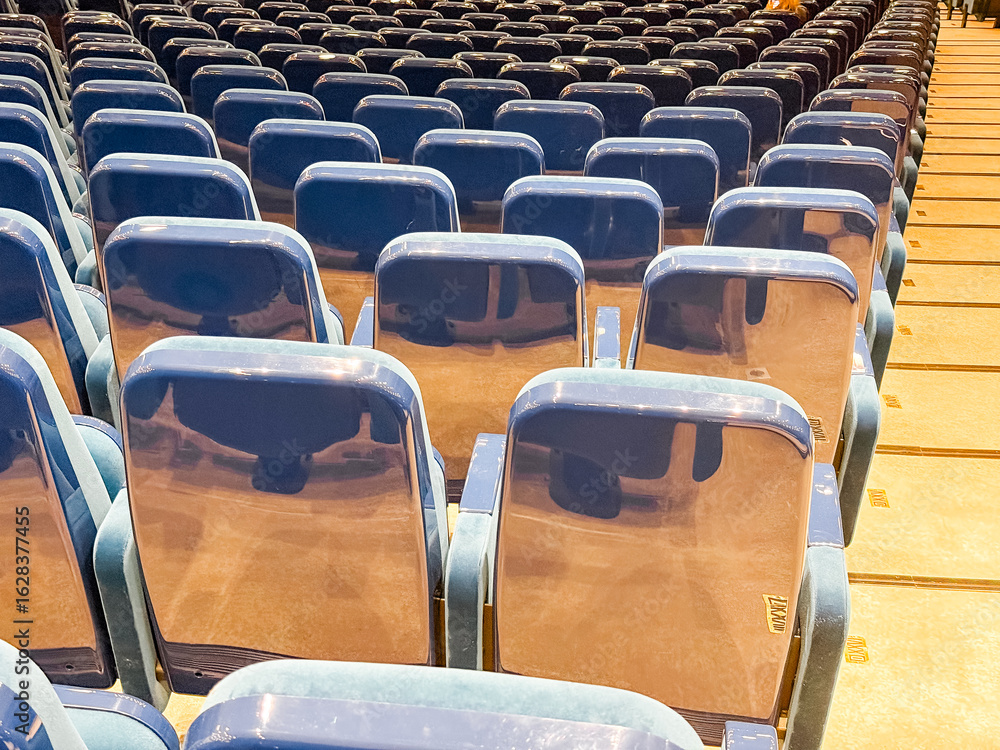 Fototapeta premium Rows of empty auditorium seats with glossy backs. Event preparation, public gathering, and modern infrastructure in an indoor conference or performance venue.