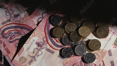 A beam of light illuminates coins and banknotes of tenge