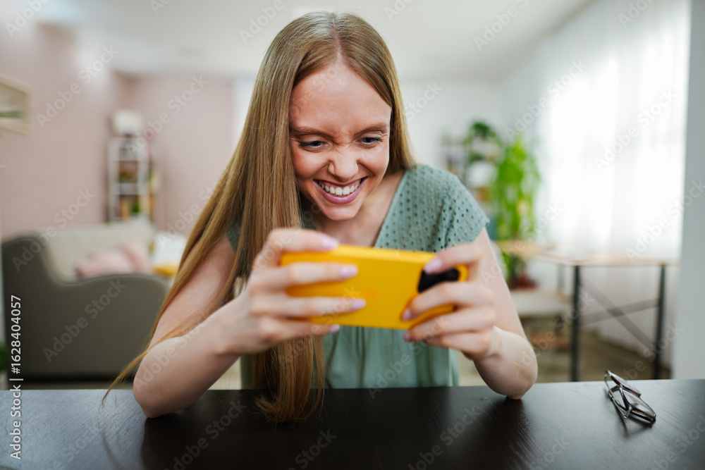 Young woman enjoying a game on her smartphone at home Young woman enjoying a game on her smartphone at home