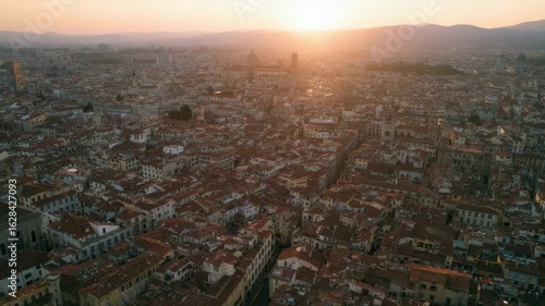 Wallpaper Mural An aerial view captures the dense urban landscape of a European city with terracotta rooftops stretching towards distant mountains under a warm sunset glow Torontodigital.ca