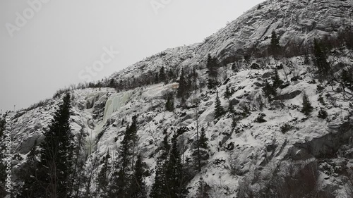 A serene snowy mountainside with a majestic frozen waterfall captivates in winter