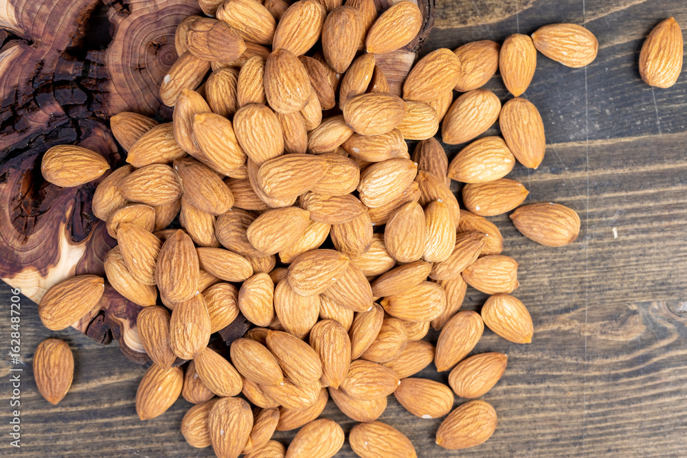 Obraz premium dried almonds scattered on a wooden table, edible delicious and crunchy brown almonds, closeup