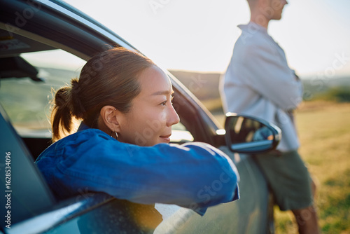 Fotografi Carefree woman leaning out of a car window, soaking in the joy of a road trip wi