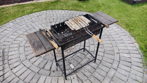 Wallpaper Mural In the yard, next to the house and lawn, a metal brazier stands on a concrete tile. Under a metal grate with a handle, coals smolder and smoke flows. Cheese in pita bread are baking over the coals Torontodigital.ca