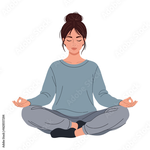 Woman with dark hair in a bun wearing gray loungewear sits cross legged on the floor, meditating with her eyes closed, ideal for wellness or lifestyle content.