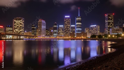 City skyline at night with reflections on water and bright lights  
