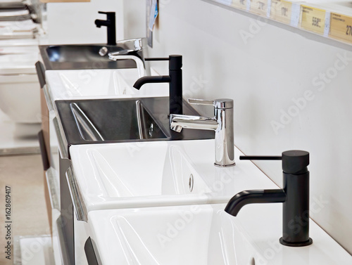 Row of modern bathroom sinks with black and chrome faucets on showroom display white ceramic basins and mixer taps in retail store sanitary ware selection for home renovation and interior design ideas