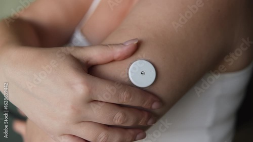 Unrecognizable female person controls location of sensor for measuring sugar in body. Device continuous glucose monitor measures sugar around the clock and helps diabetics.