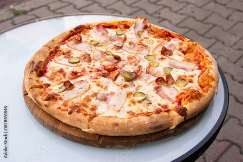 Wallpaper Mural Delicious pizza topped with ham, pickles, and cheese, served on a wooden board, showcasing a mouthwatering dish perfect for sharing and enjoying with friends Torontodigital.ca