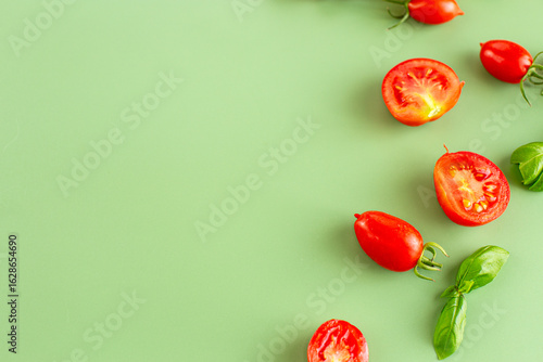 Fresh red tomatoes scattered with basil on pastel surface